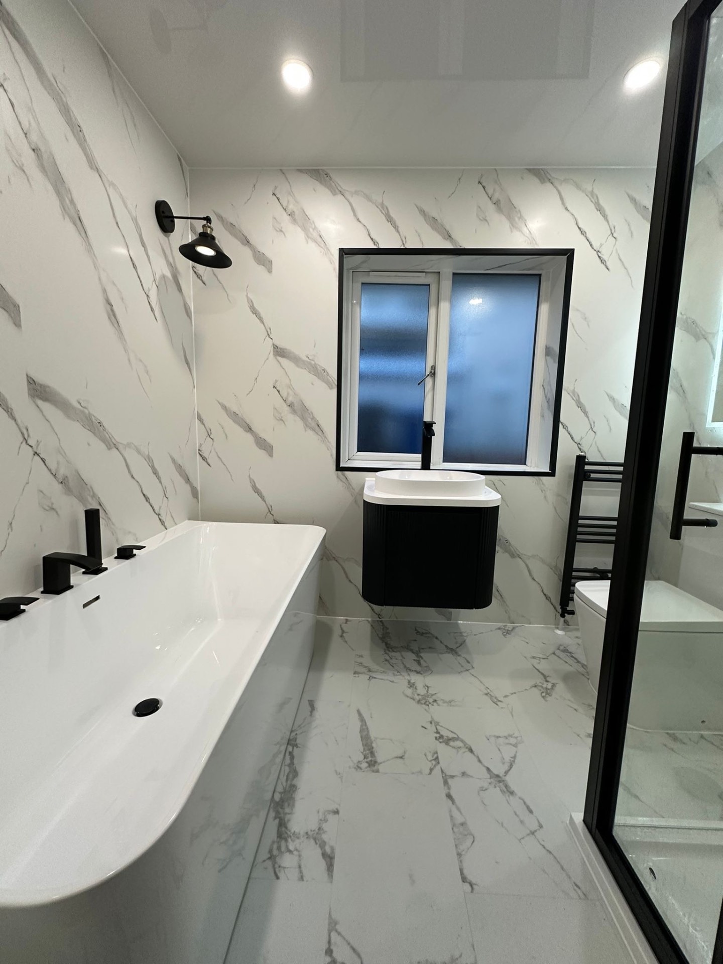 White marble-effect bathroom with a freestanding bath and black fittings